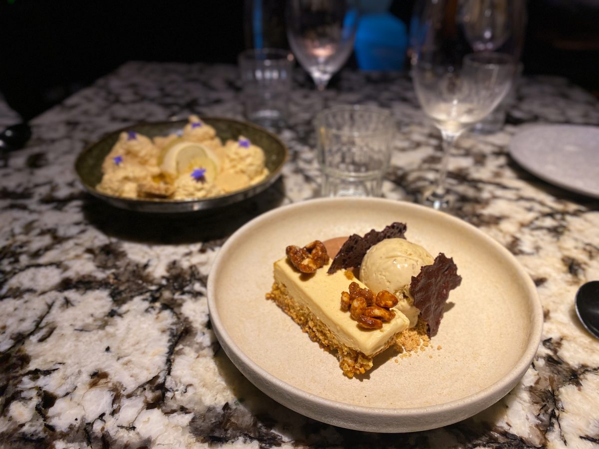 In the foreground, a dessert with peanuts and chocolate, with a different bowl of dessert in the background. 