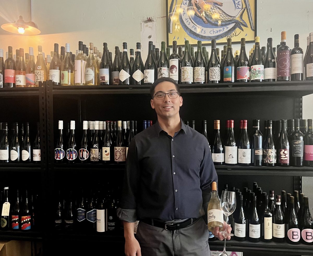 A man standing in front of a shelf of wine bottles