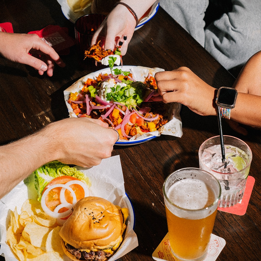 Hands reaching for food and drinks, photographed from above