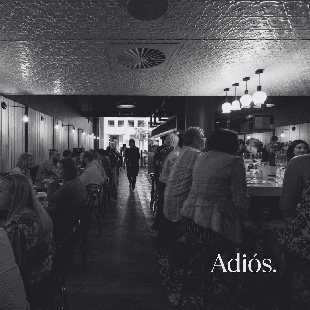 Black and white photo of restaurant interior with text 'Adiós.' in the corner.