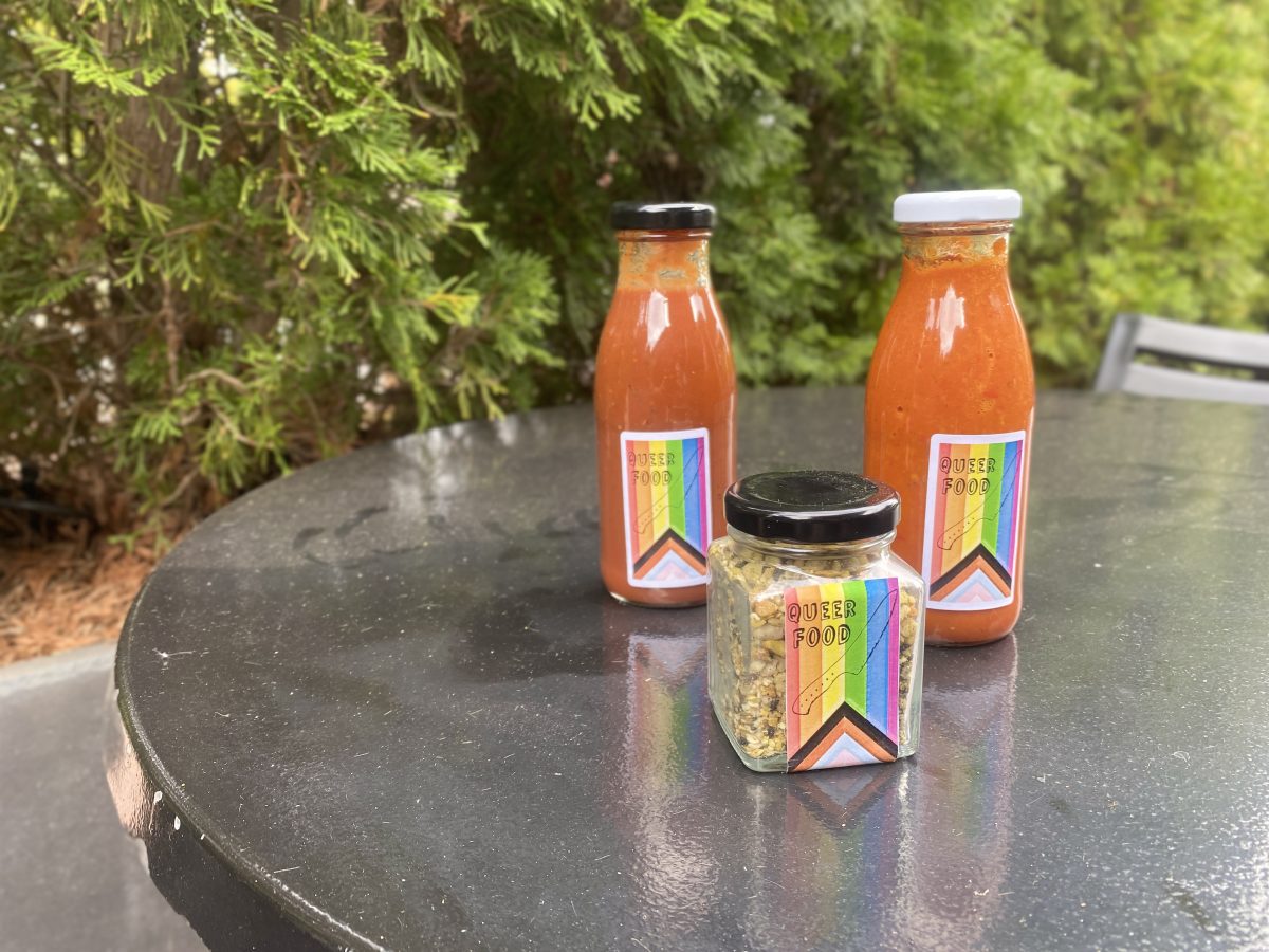 Two bottles of sauce and a jar of dukkah with rainbow Queer Food branded labels