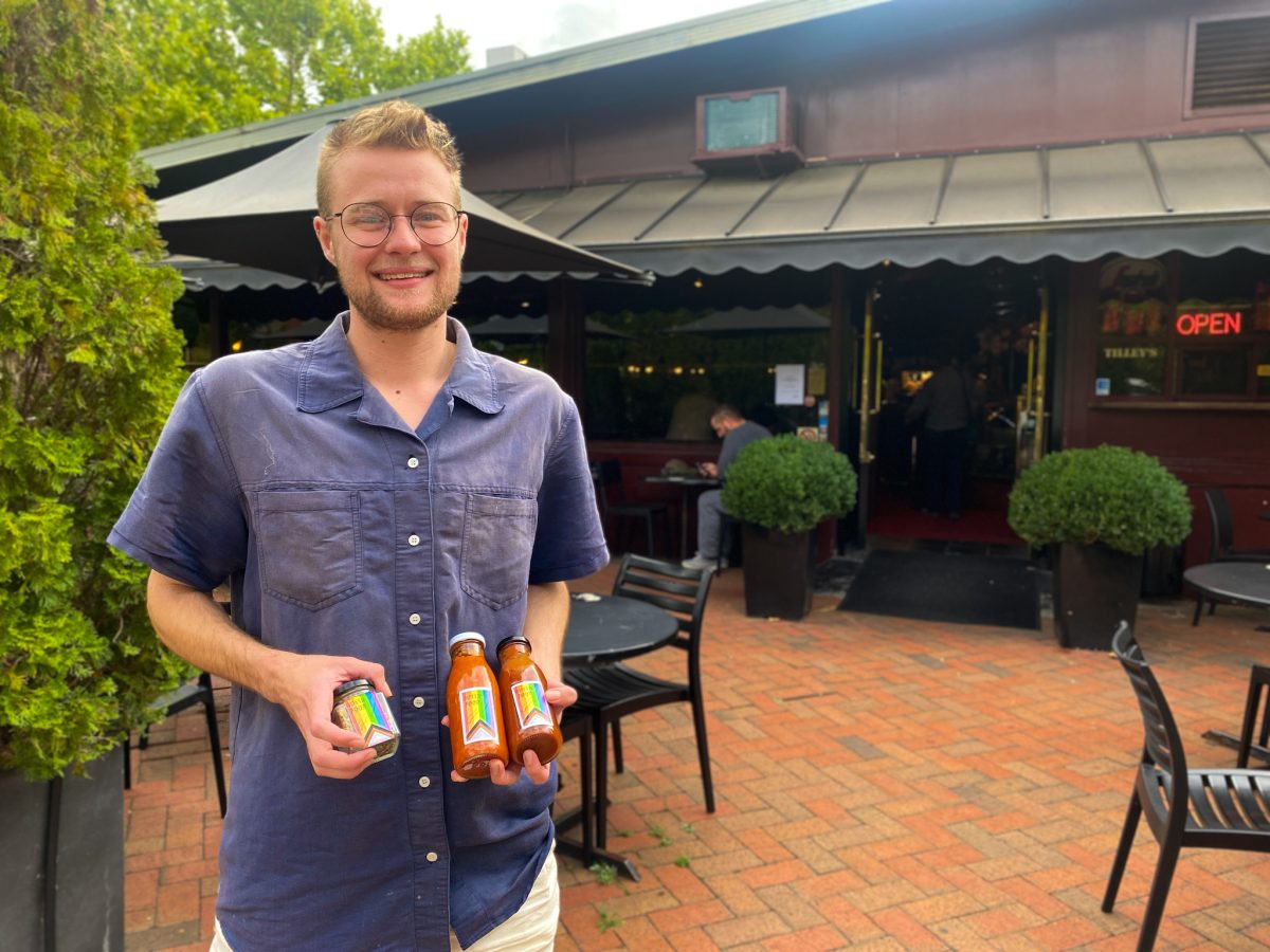 Andy holds Queer Food products outside a cafe