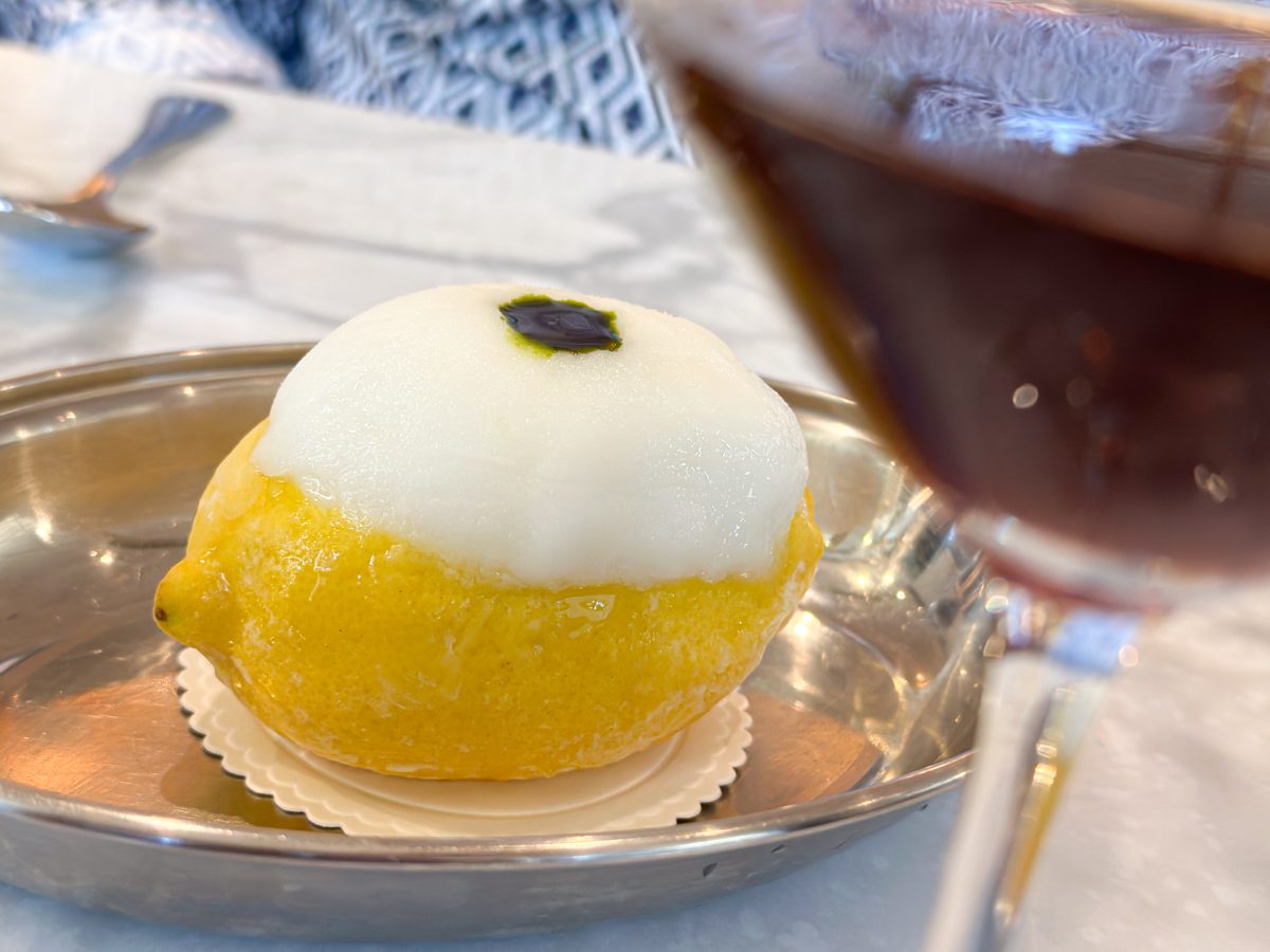 A whole lemon on a silver plate filled with white sorbet, topped with green oil. 