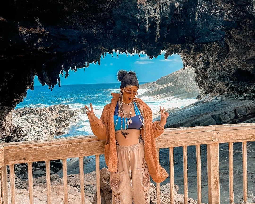 woman standing near a rock formation near the sea