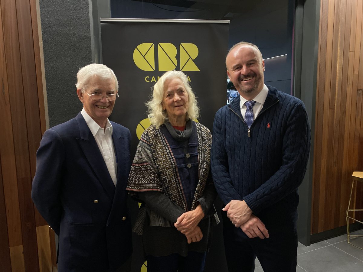 Three people smile in front of CBR banner