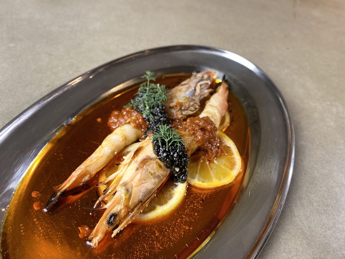 Two grilled prawns on silver tray with lemon slices.