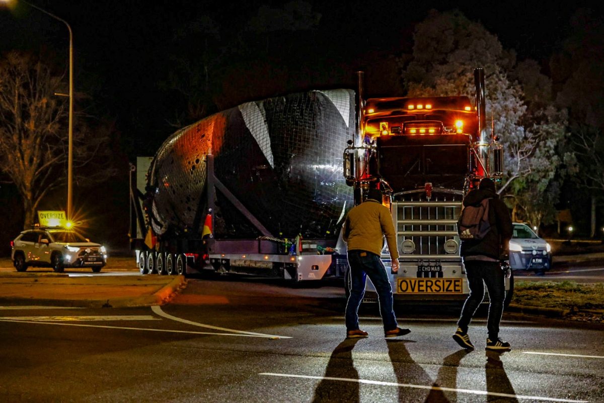 Men direct oversized truck into entrance to the National Gallery in Canberra