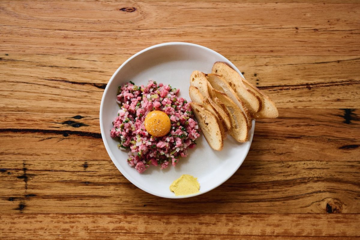 Steak tartare dish on wooden table.