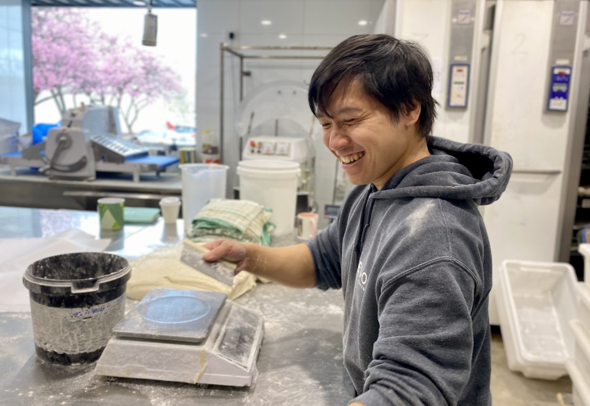 Baker smiles while weighing dough.