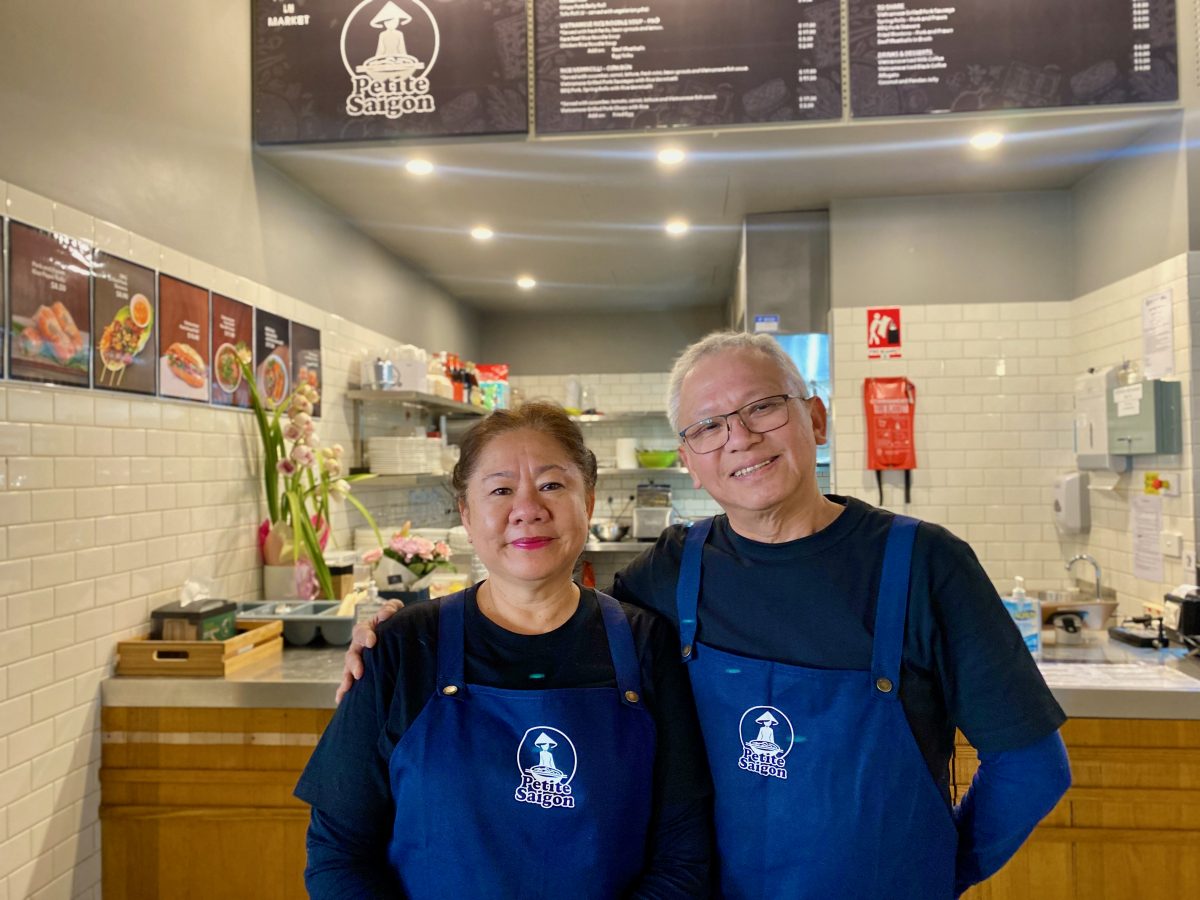 Vietnamese couple Bun Luc and Tien Trang smile at the camera, wearing Petite Saigon aprons