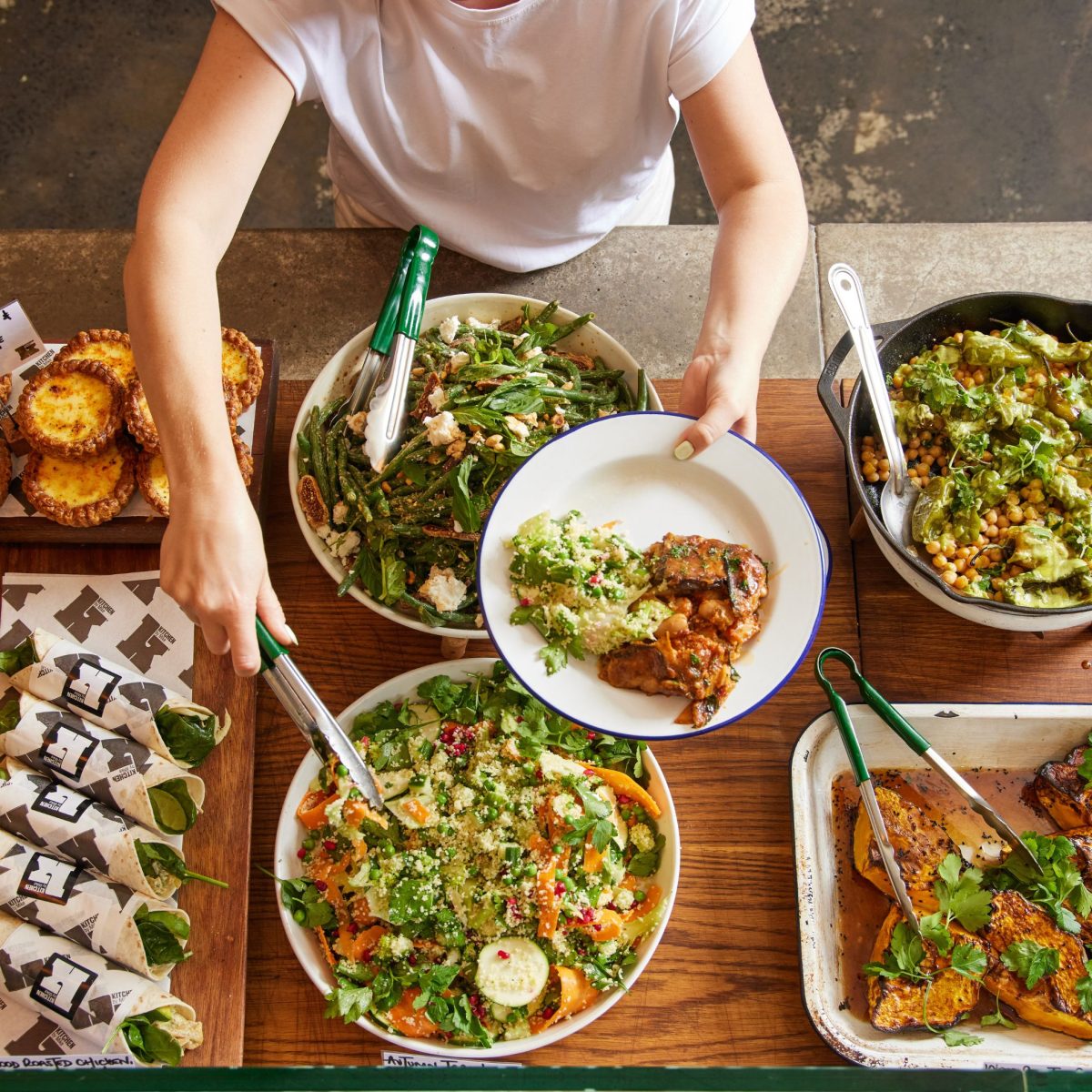 Shot from above of person dishing up a plate from a buffet of food. 