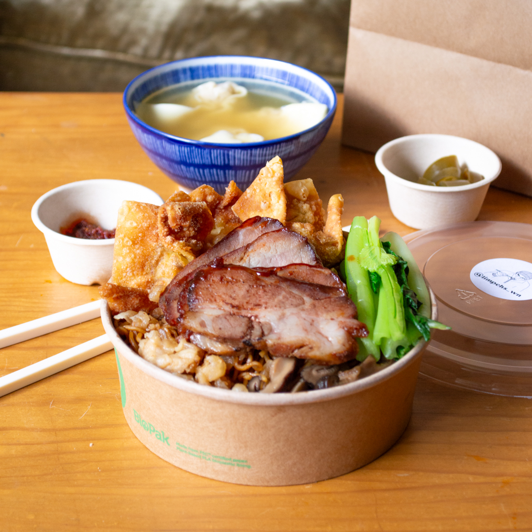 A takeaway container heaped full of roast pork, noodles and dumplings.