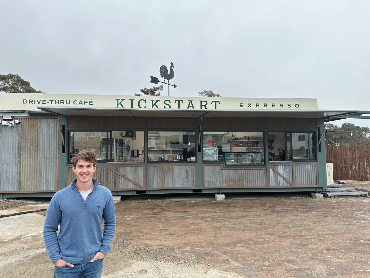 Man stands outside drive-thru coffee location.