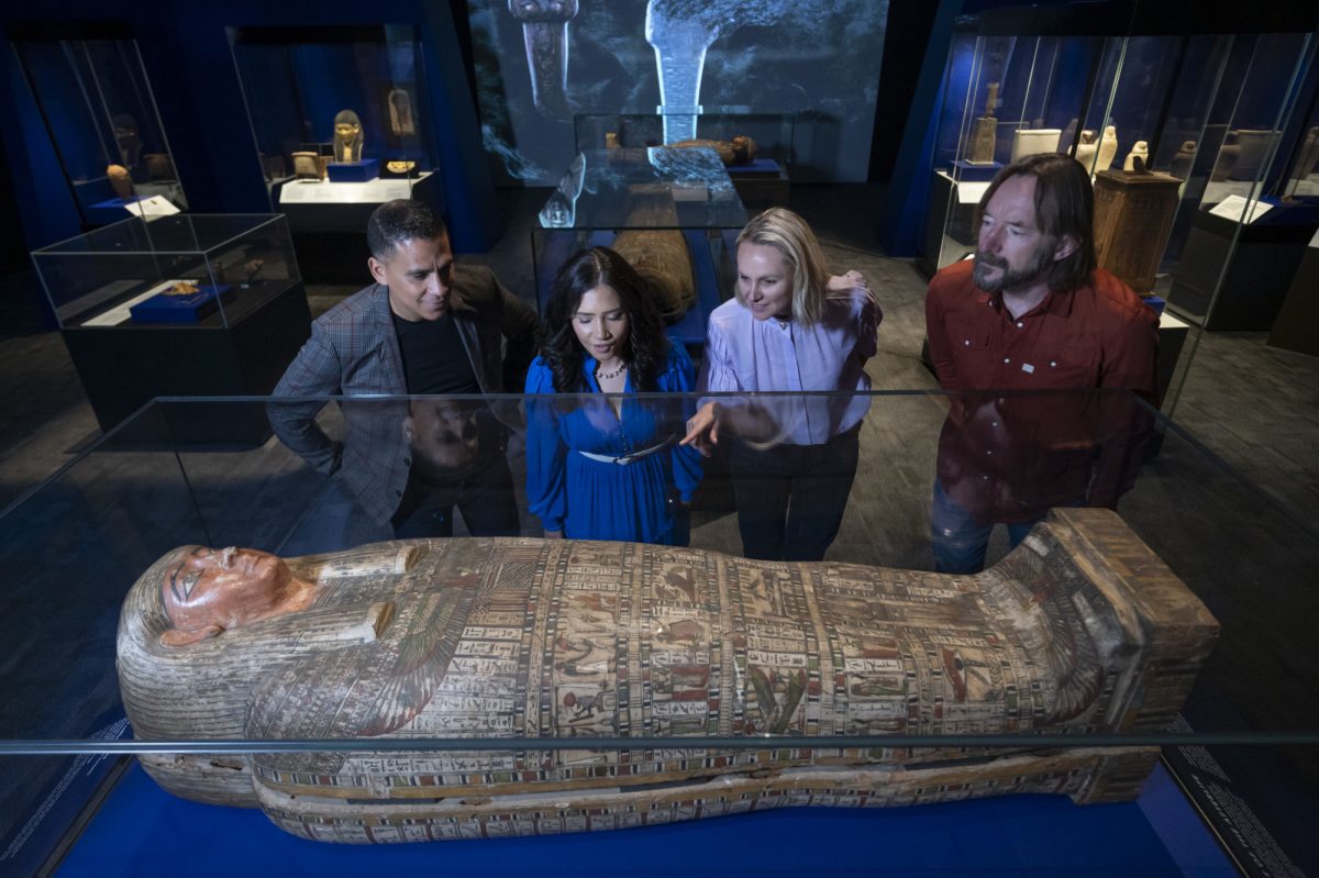 Group of four people look at mummy in case