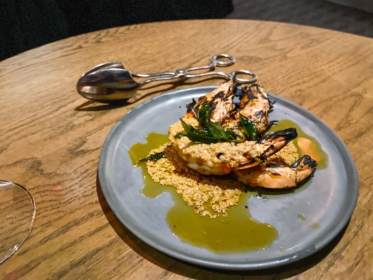 Two prawns, grilled and covered with sauce and fried curry leaves.