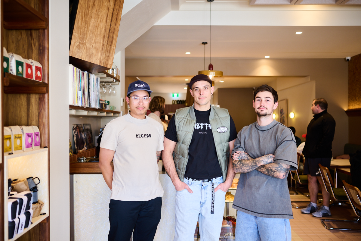 Three men stand in cafe.