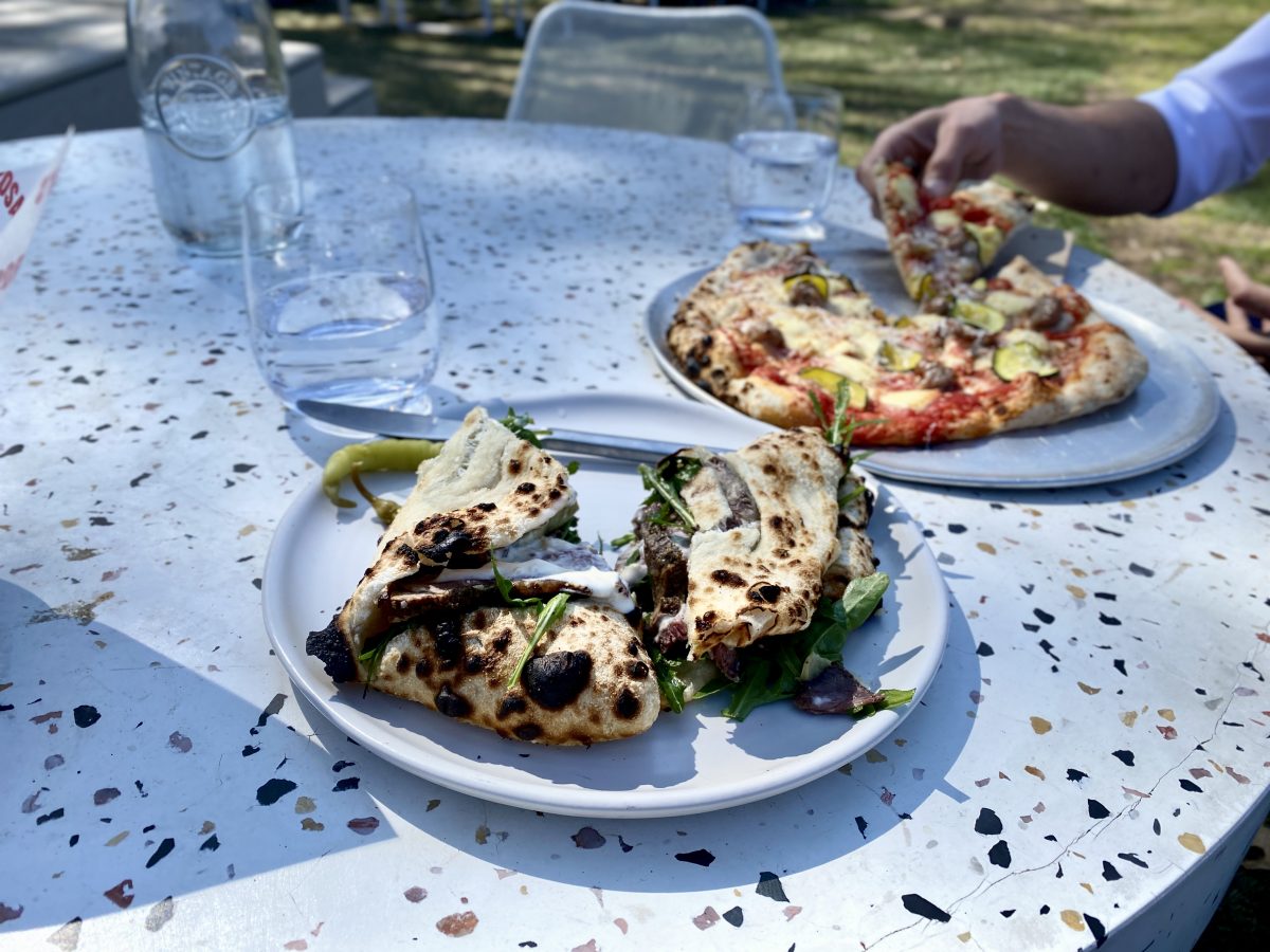 A folded pizza dish filled with beef and rocket on a terrazzo-patterned table.