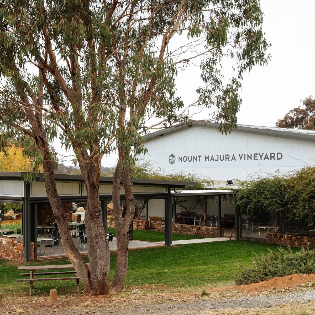 White shed with signage reading Mount Majura Vineyard, and an attached undercover dining space.