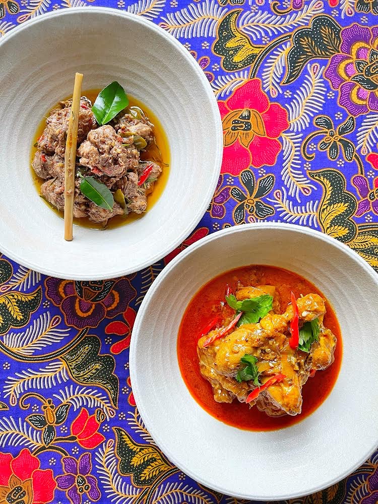 Two bowls of curry on a patterned table.