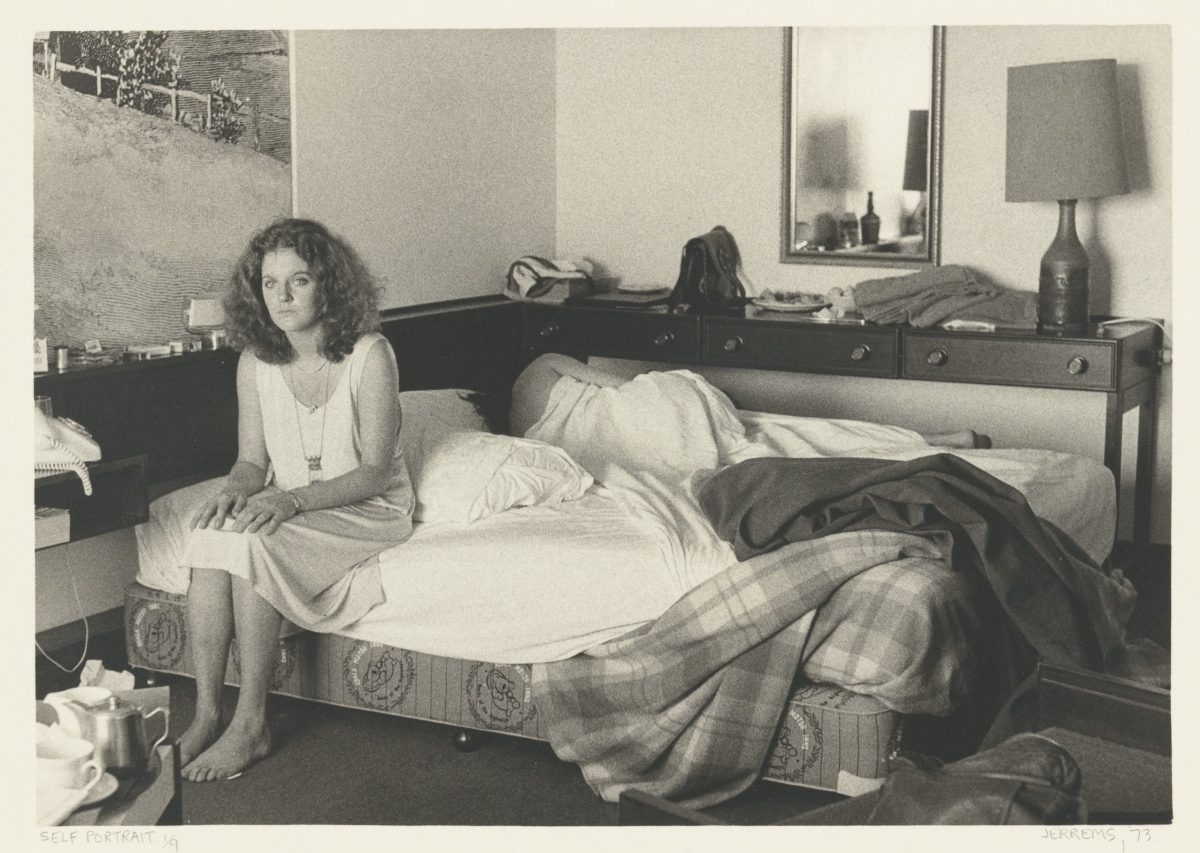 Woman sitting on edge of bed in a room