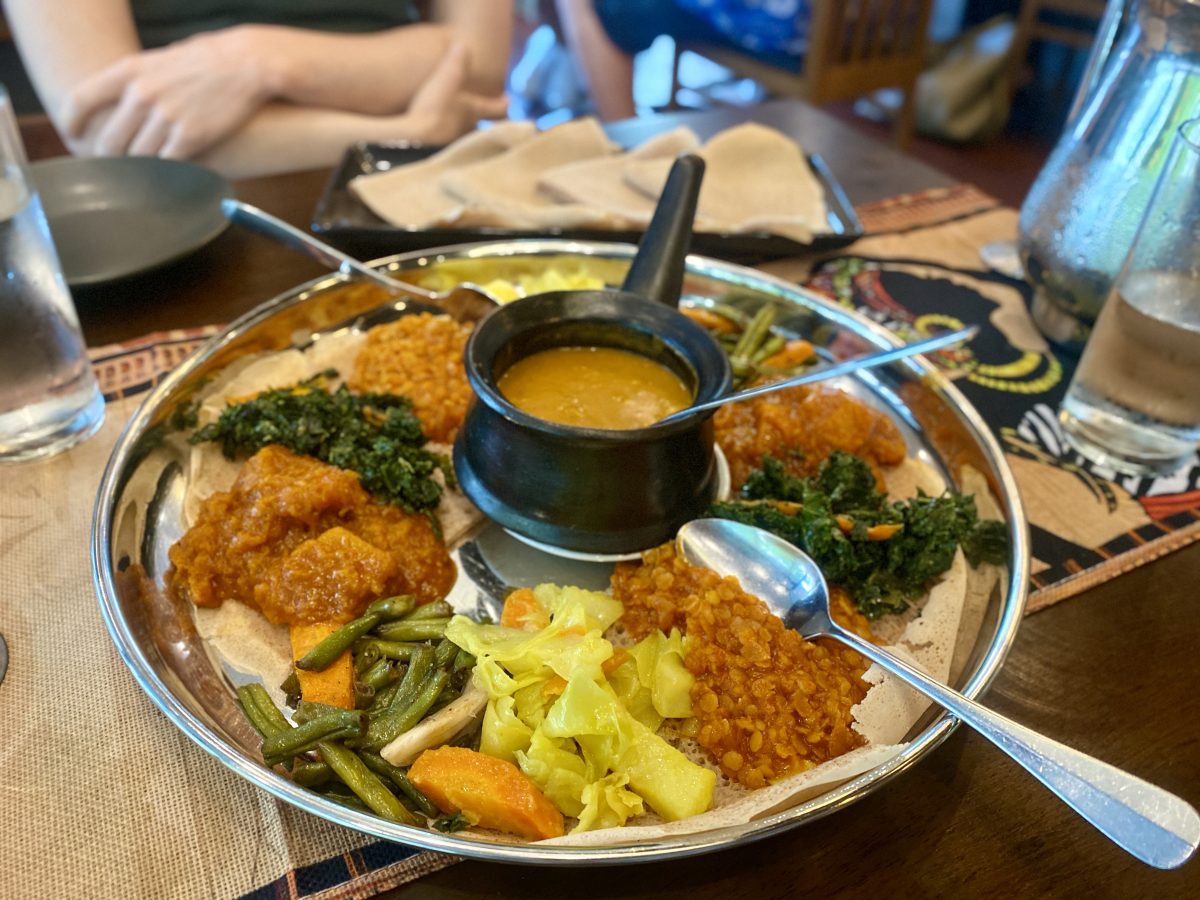 A platter of colourful dishes with folded flatbreads in the background.