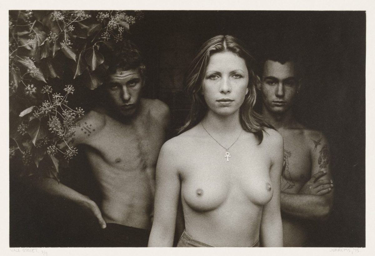 Three topless figures with a tree in the background