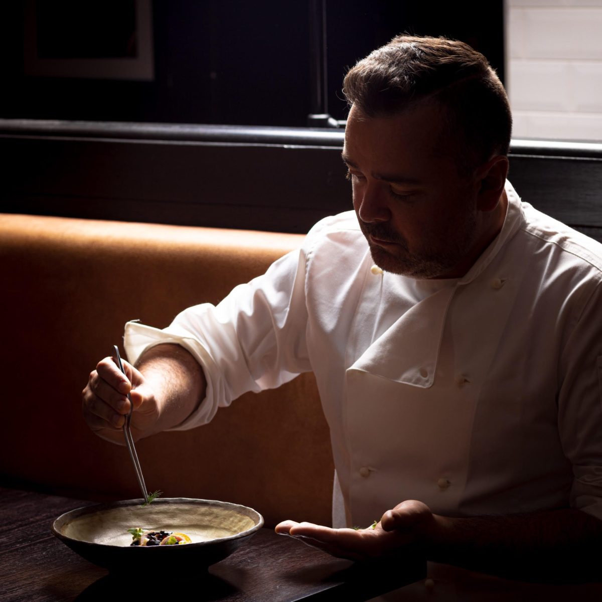Chef in shadows plates up a dish