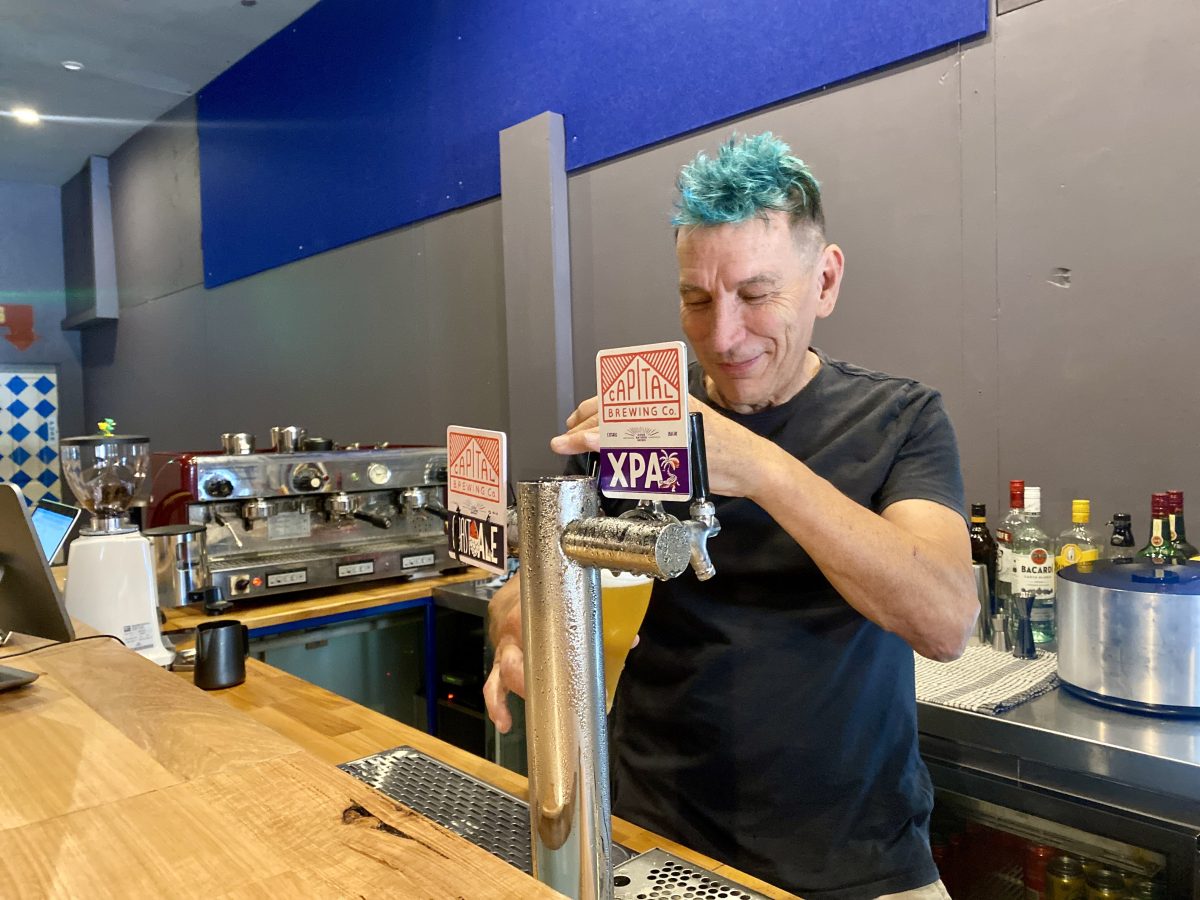 Dave Howe with blue hair pours a beer.