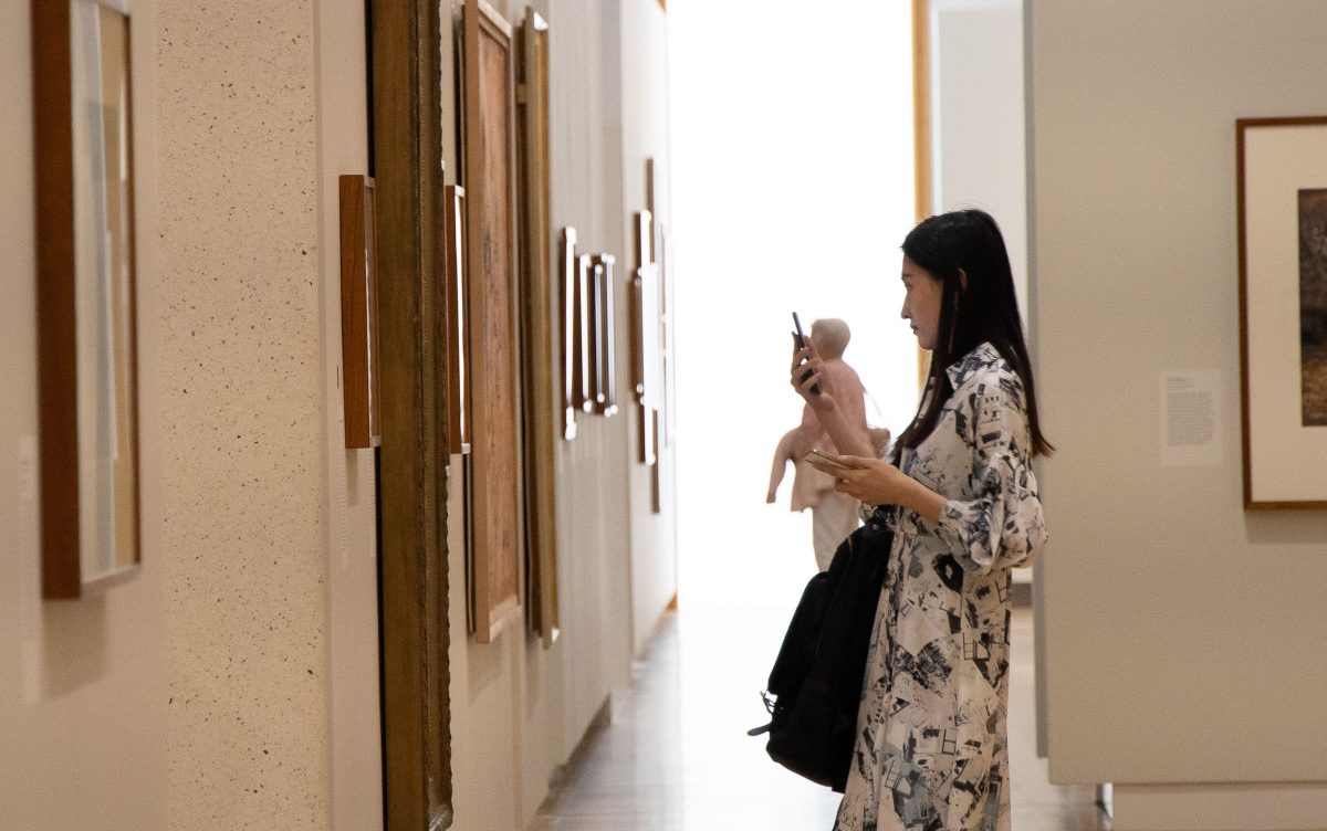 A woman uses her phone to engage with art work at the National Portrait Gallery