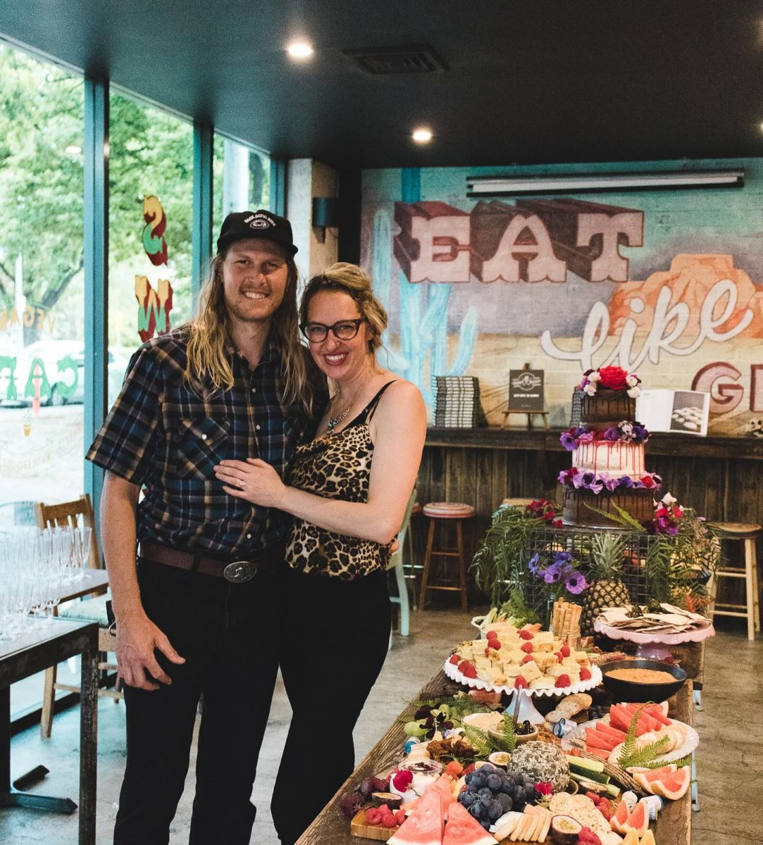 Two people pose next to a long table of food