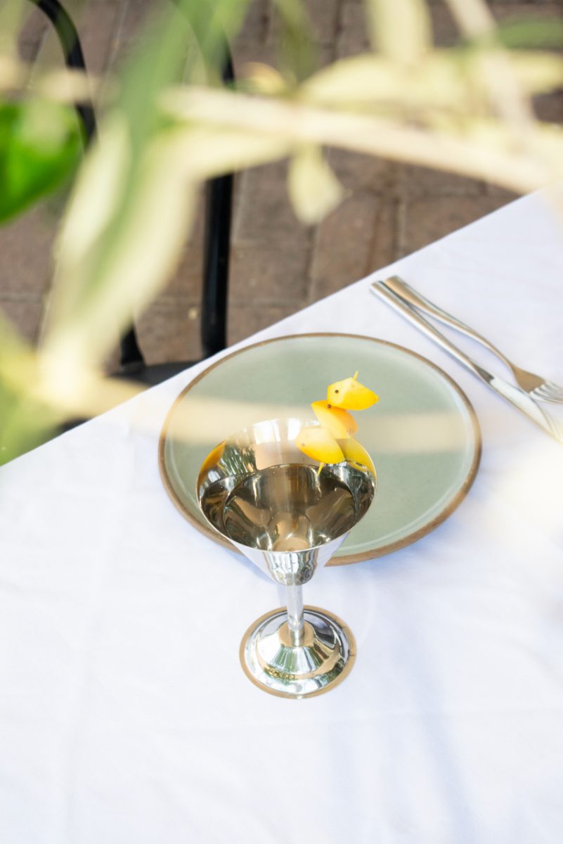 A martini in a silver martini glass on a white tablecloth.