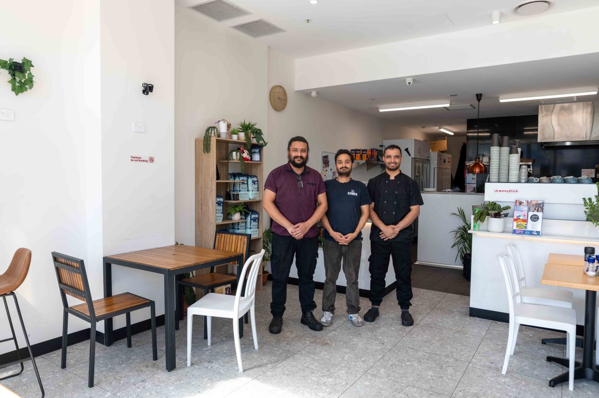 three men standing in a cafe