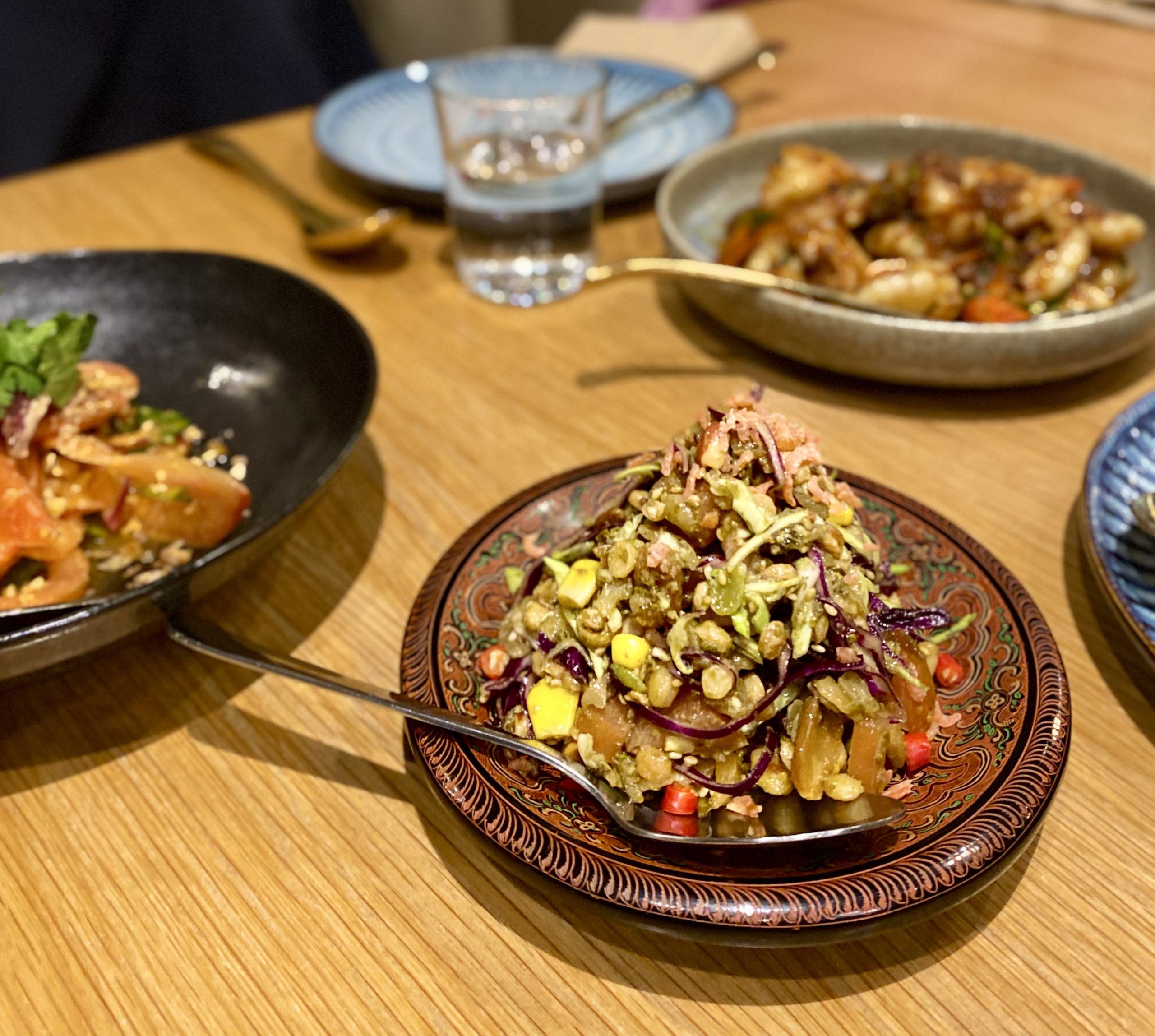 A dish on a traditional lacquer bowl with other dishes in the background.