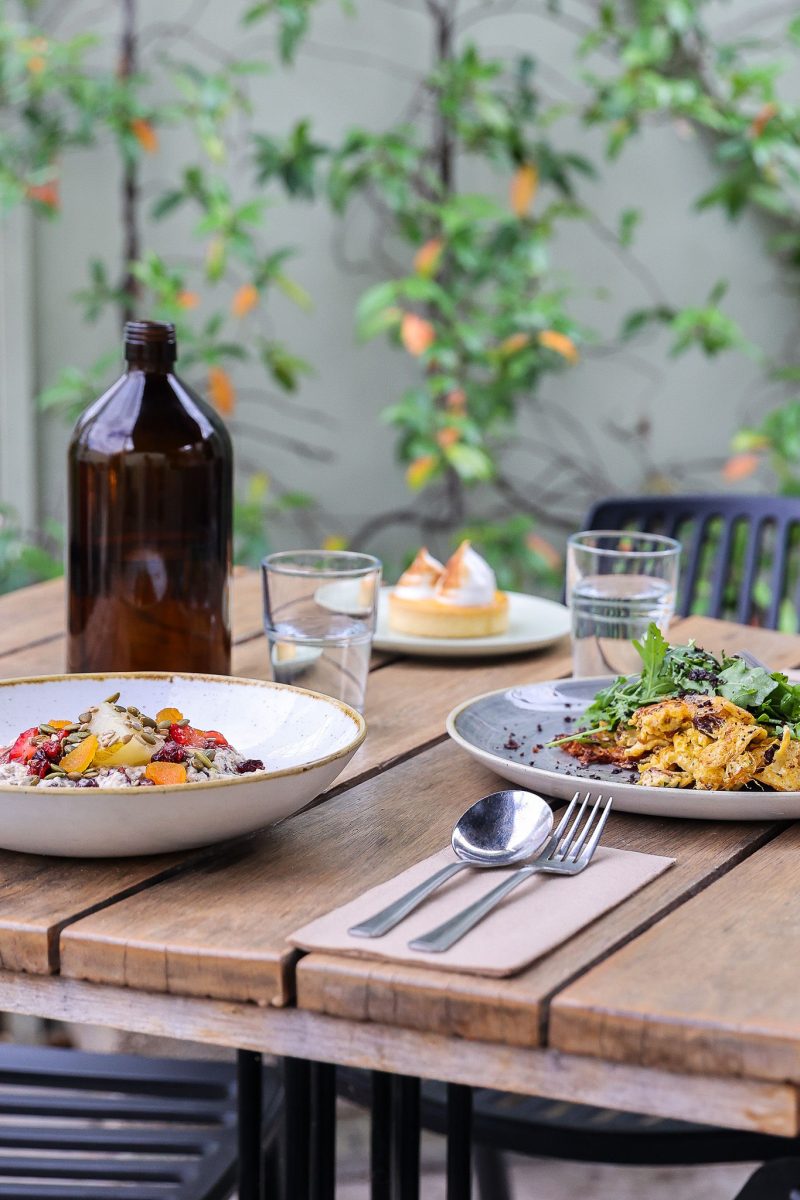 An outdoor table with plates of food.