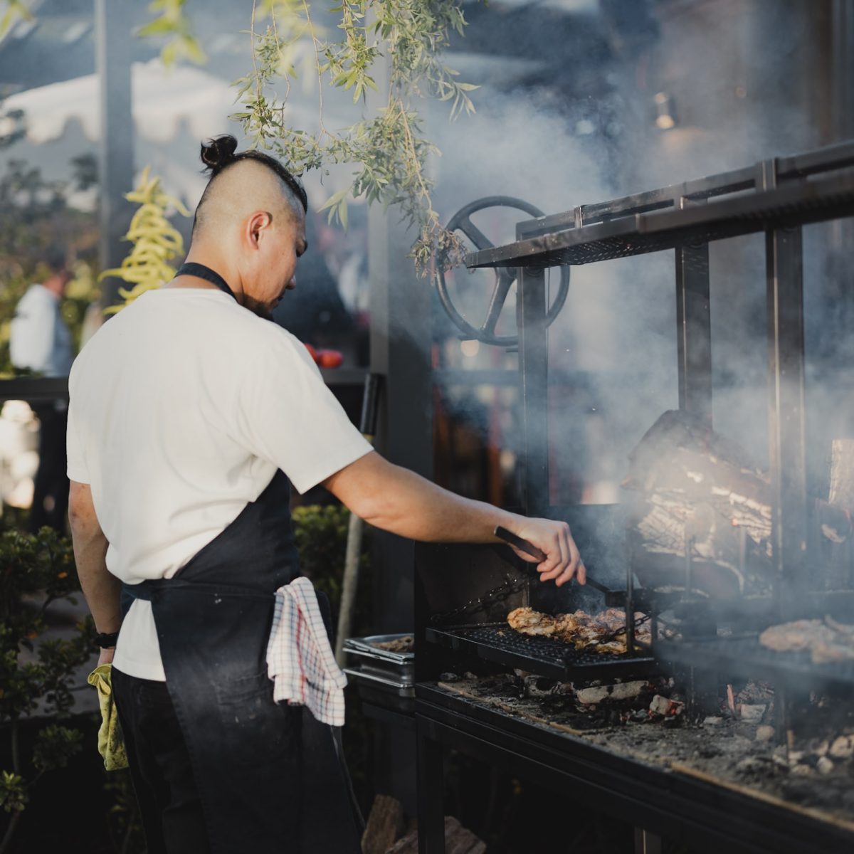 A chef cooking over a charcoal barbecue grill