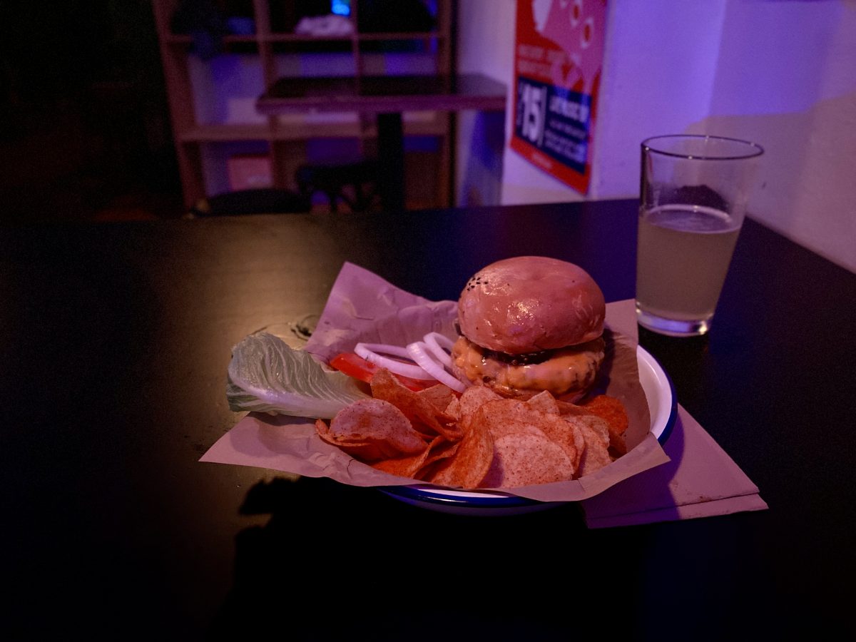 A burger with crisps and a beer.