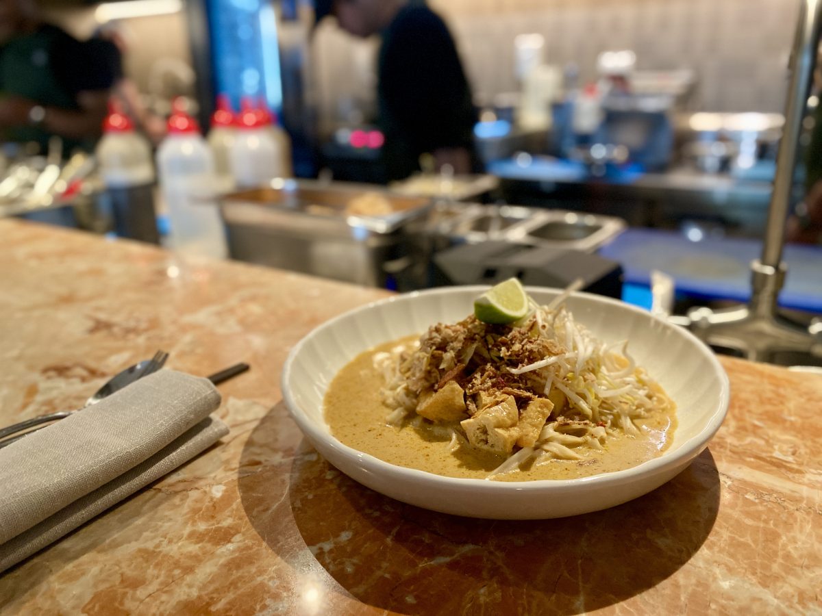 A shallow bowl of laksa on a pink marble bench.