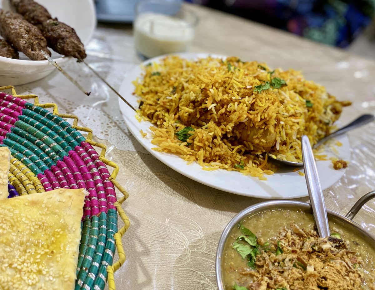 A dish of biryani, a curry, some skewered meat and flatbreads with sesame,