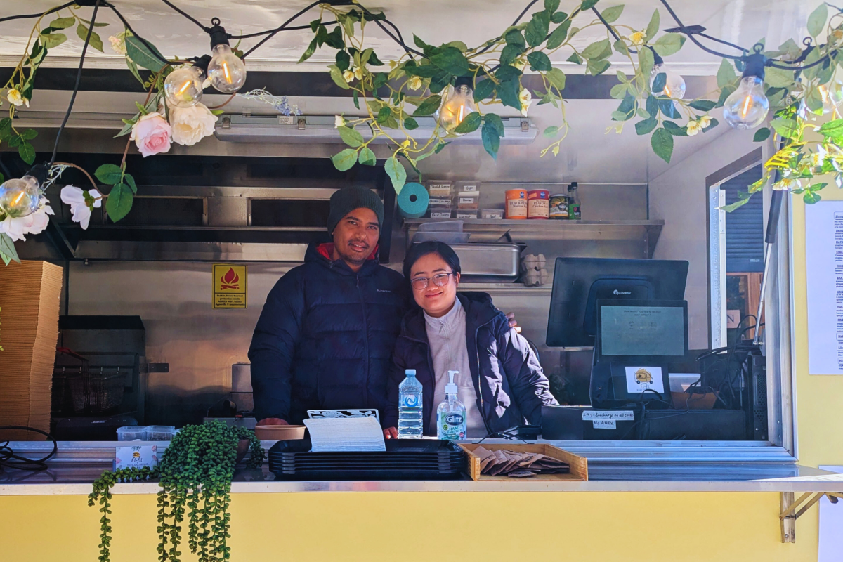 Man and woman smile in food truck window.