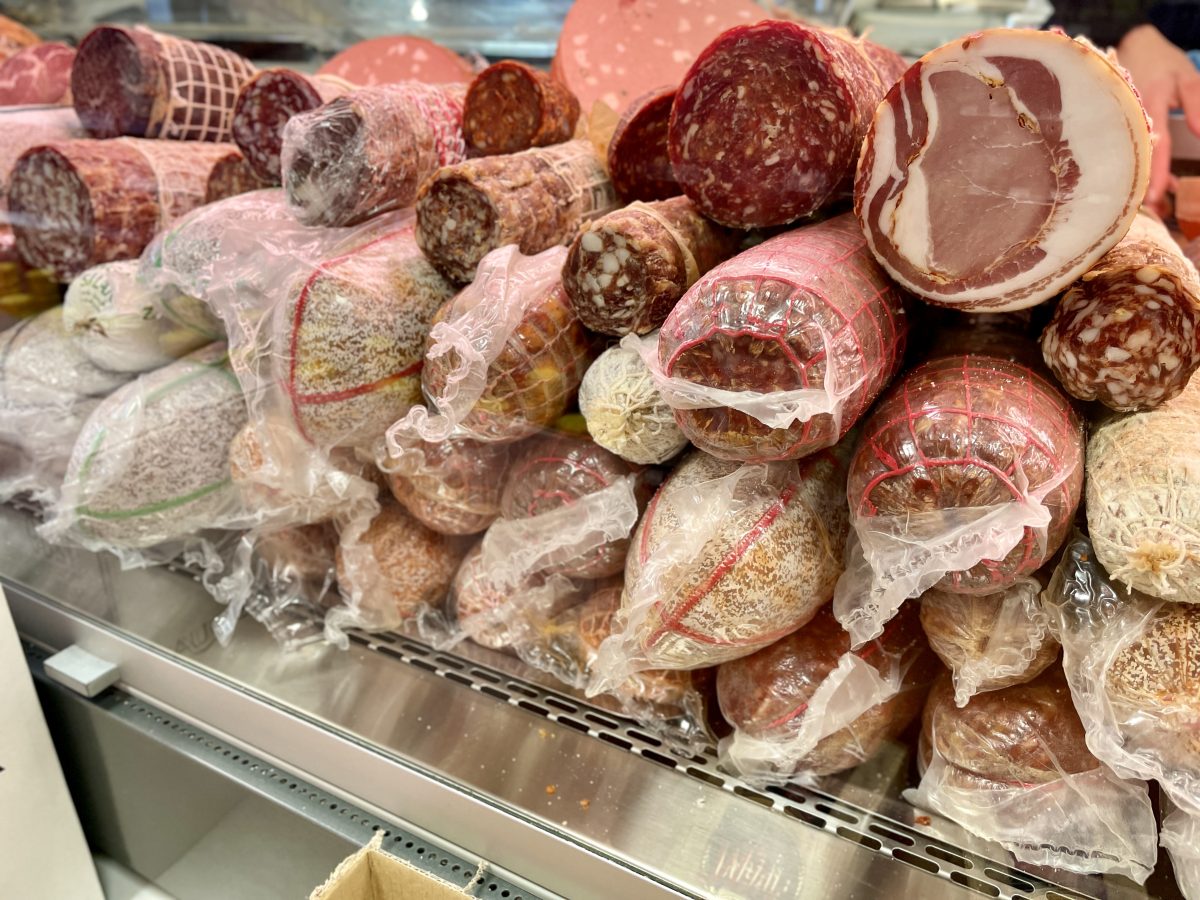 A display fridge stacked with many different cured meats.