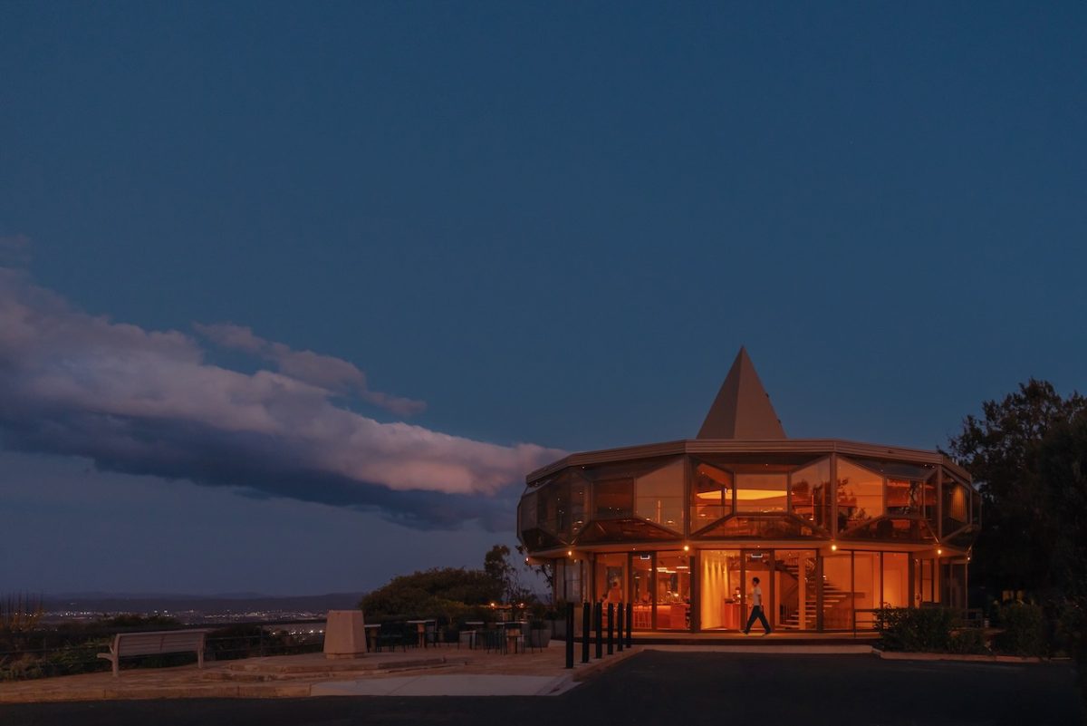A carousel-shaped building glows with warm light against a dusk sky,