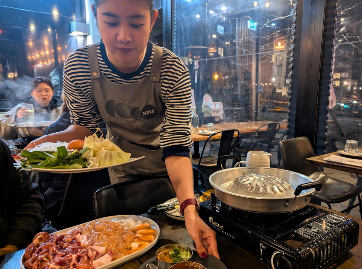 Waitress serving platters of food for Thai BBQ.