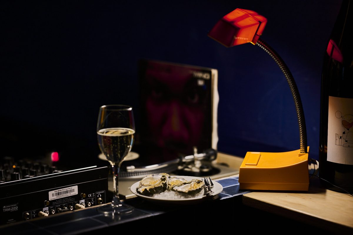 Wine glass and a plate of oysters under a retro looking lamp
