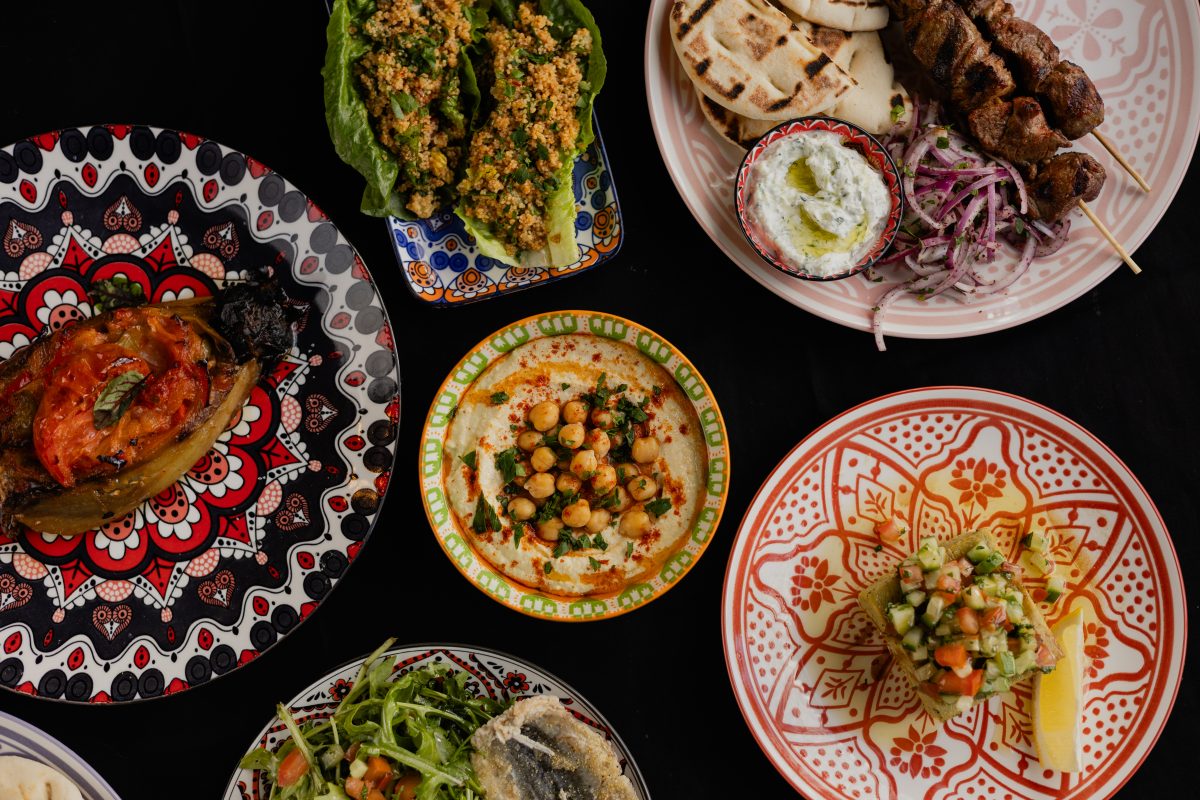 A top-down shot of Turkish dishes on colourful crockery against a black background.