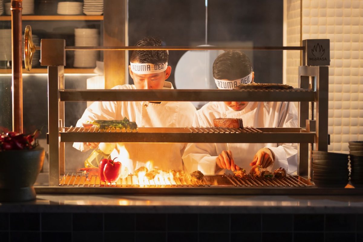 Two chefs work on a hibachi grill.