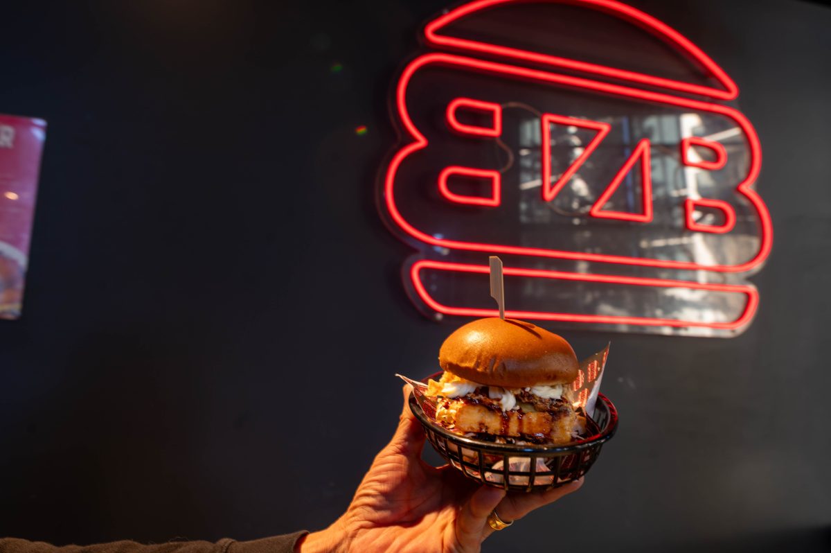 a burger in front of a neon sign.