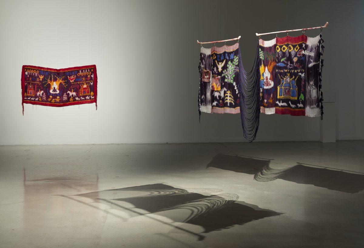 A photograph of a gallery space with textile hangings