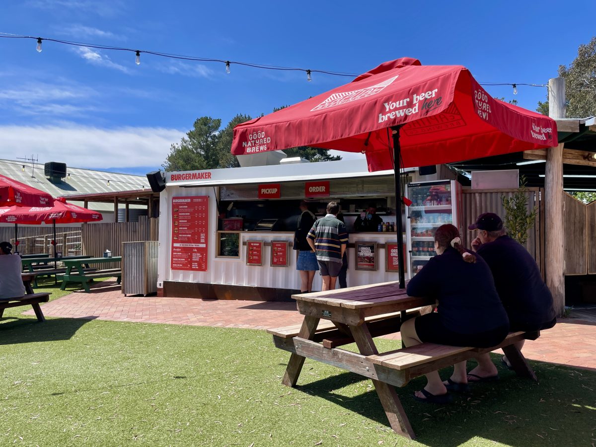 Picnic table with umbrella in front of bar in shipping container.