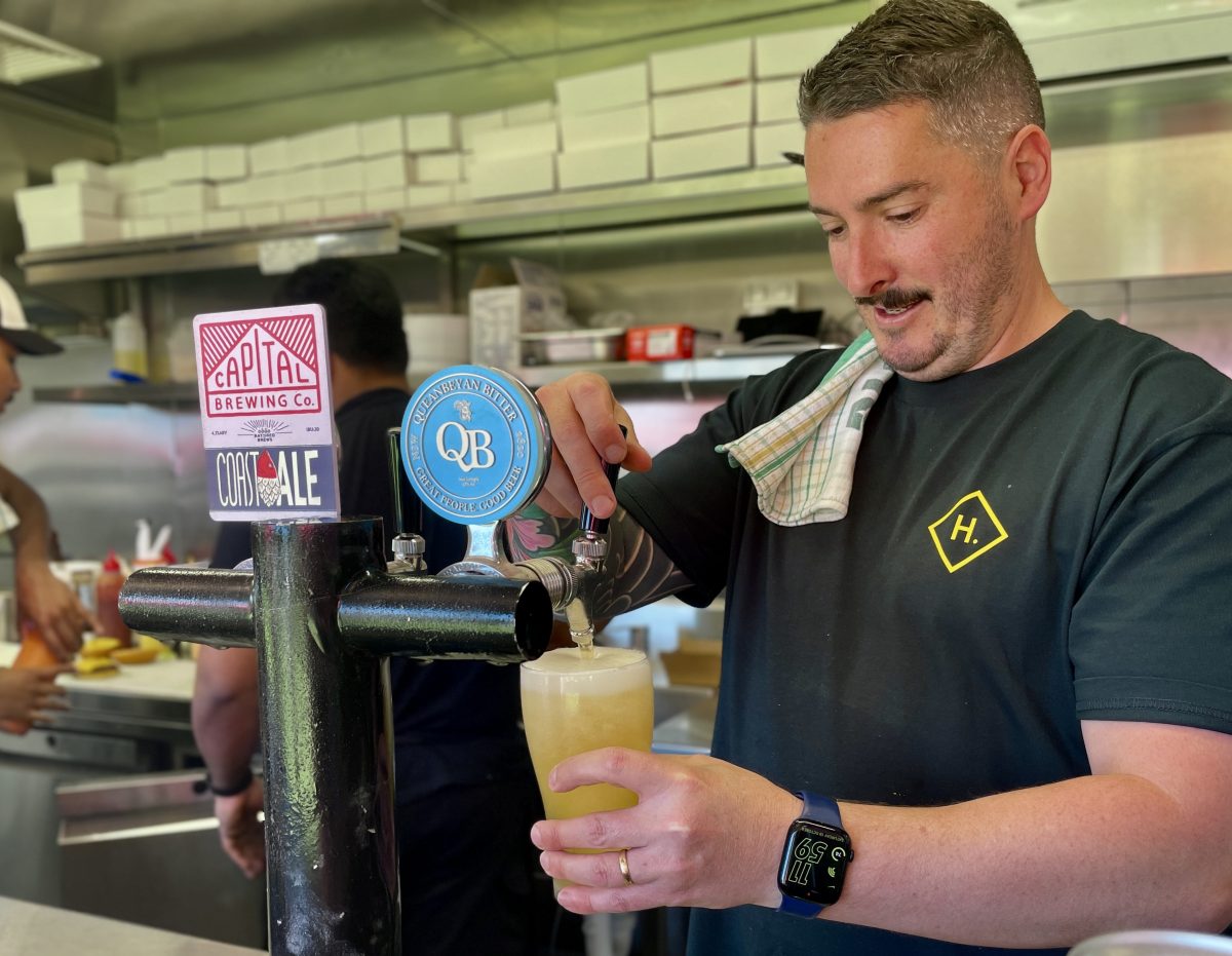 Man in green t shirt pours a beer.