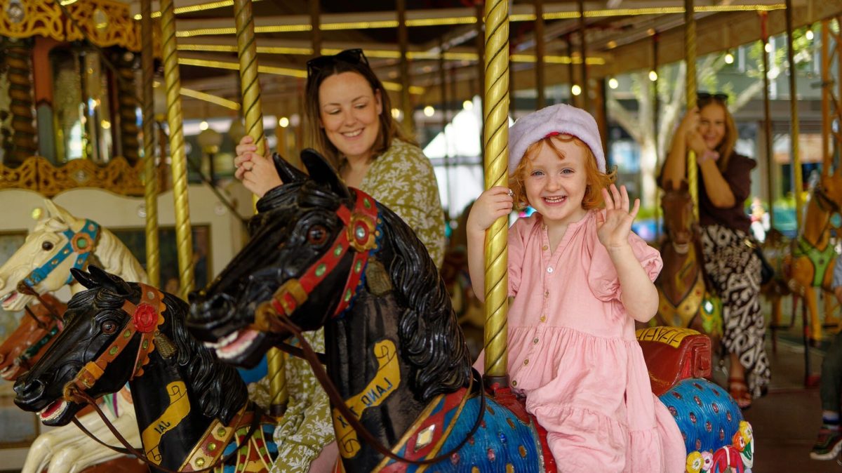 a child and adult riding on a merry go round